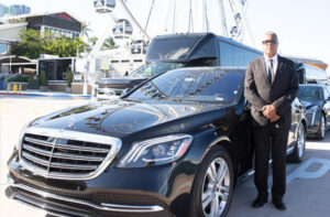 Driver posing beside a black Luxury Sedan