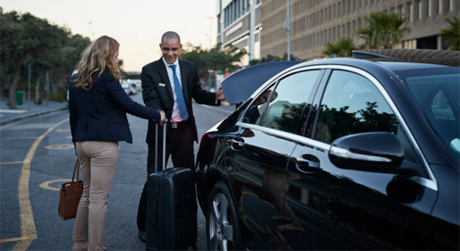Airport transfer service with driver picking up the customer's bag to put in the trunk