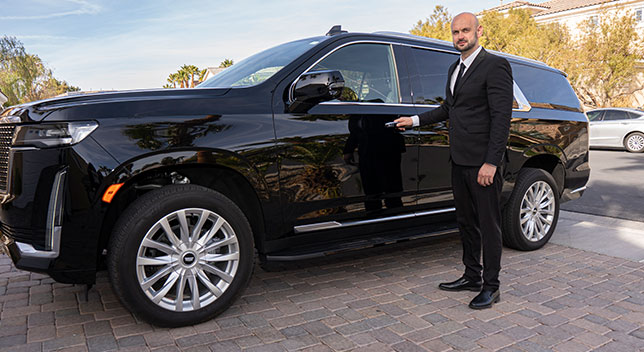 Professional driver with his hand on the door handle of a black SUV